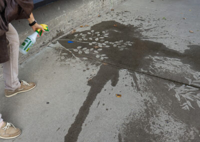 Un homme asperge le sol avec un arrosoir pour voir l'œuvre artistique de l'artiste Loren Williams dessinée au sol